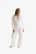 A woman modeling a white long-sleeve top and matching wide-leg pants against a plain white studio background.